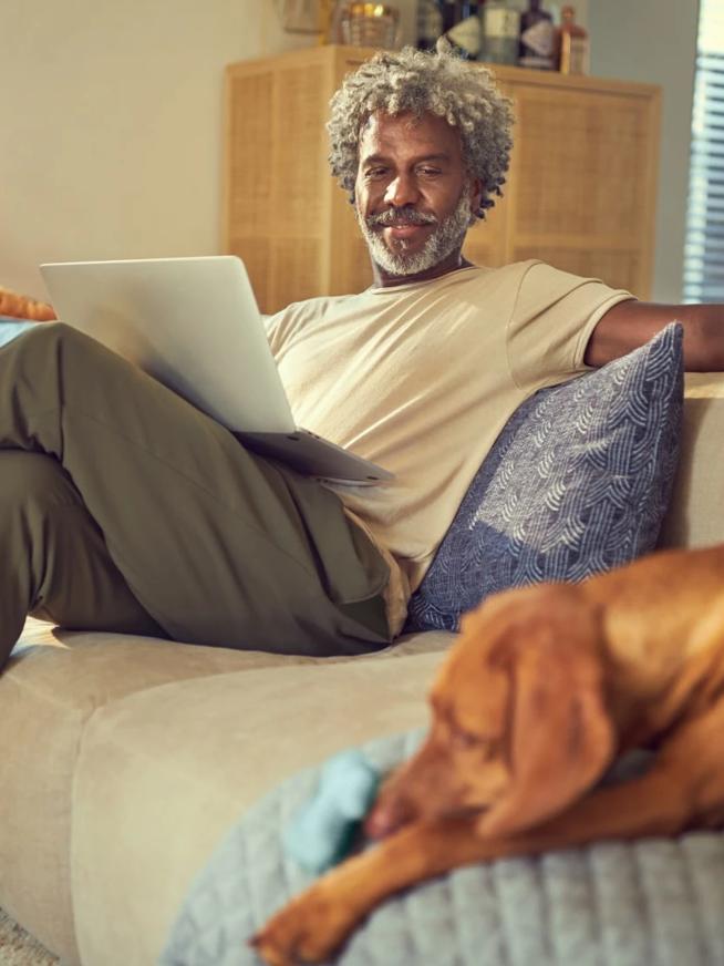 Homem no sofá de casa com o cachorro fazendo compras online