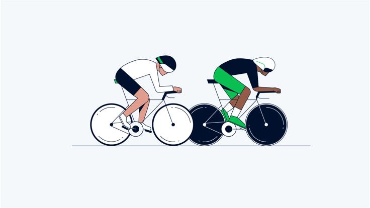 Two cyclists in a race. One in a white and black jersey with black helmet and the other with a green and black jersey with white helmets. The cyclist with the black and green jersey is in the lead.