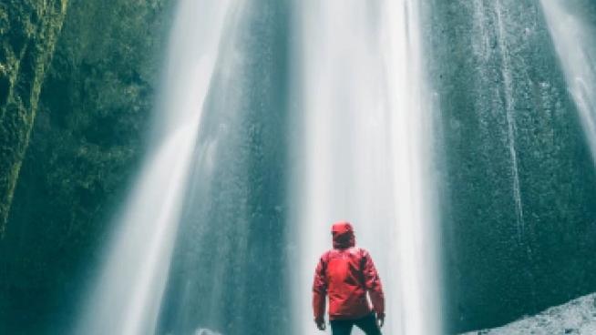 Man standing in front of waterfall