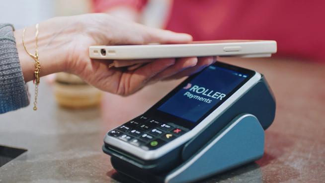 An image showing someone making payment with their phone on a ROLLER Payments terminal