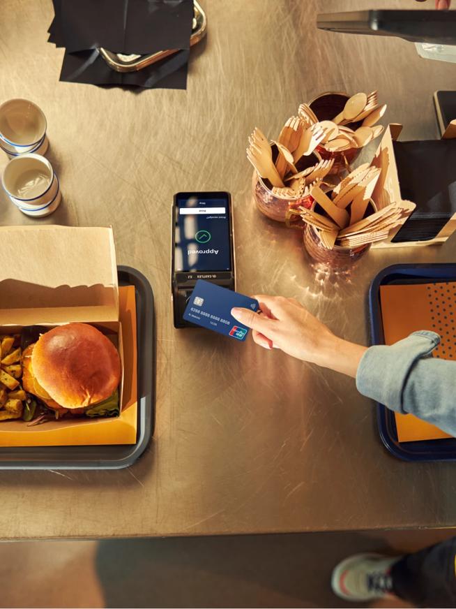 Phone and terminal payment with food beside burger fries