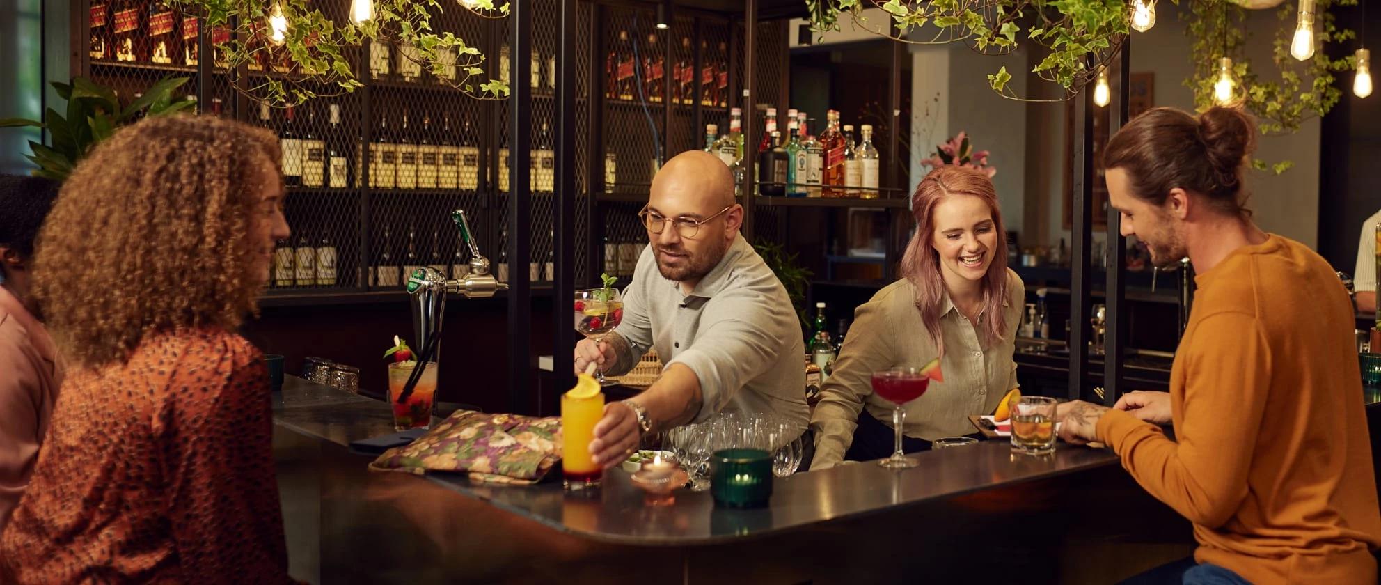 Two bartenders delivering drinks to customers